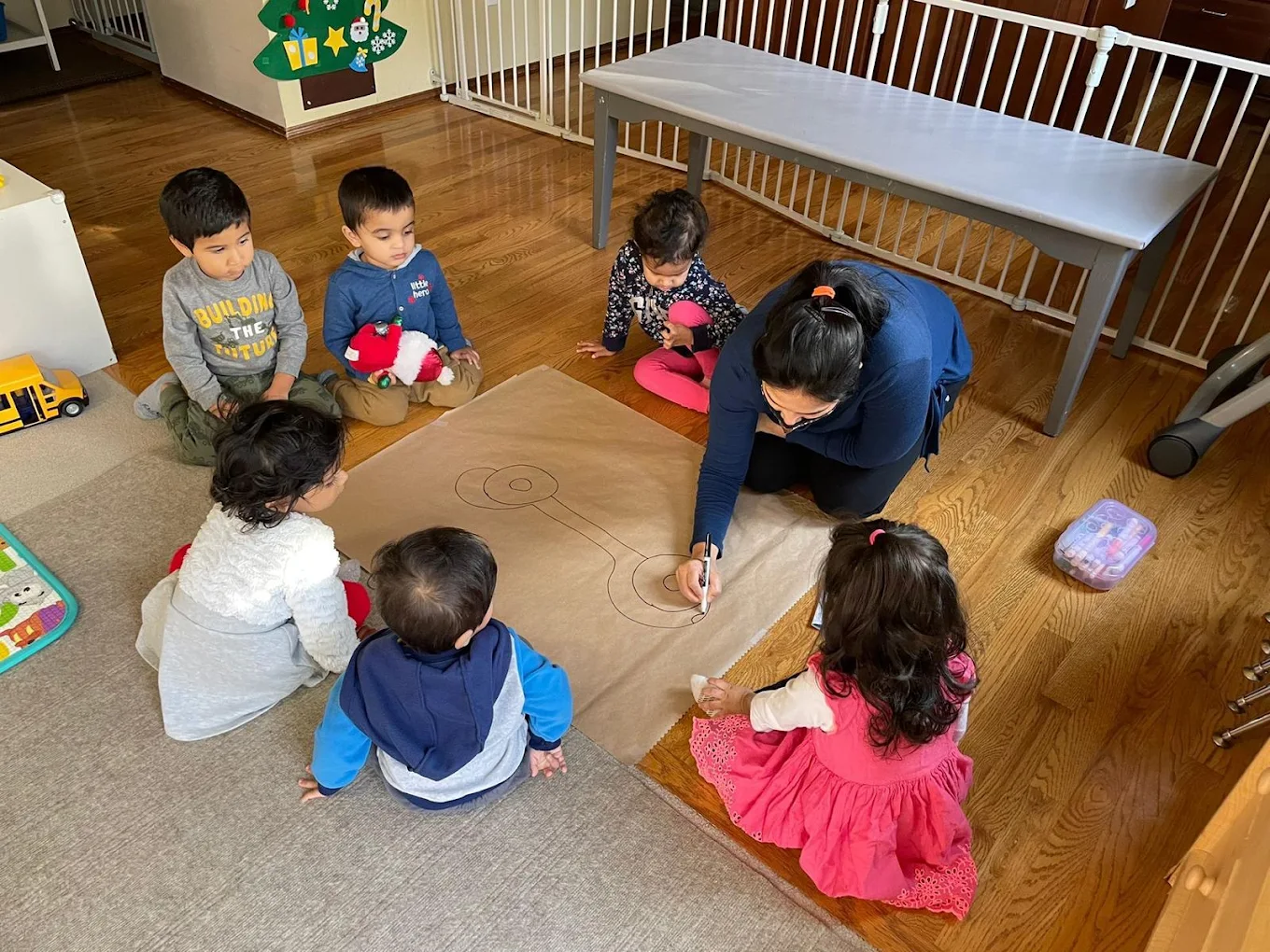 A teacher and children gathered around a group drawing activity at Strawberry Fields