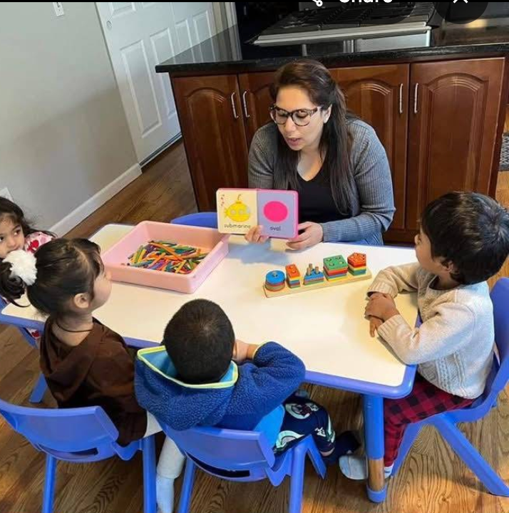 A teacher sharing a book with children around the activity table